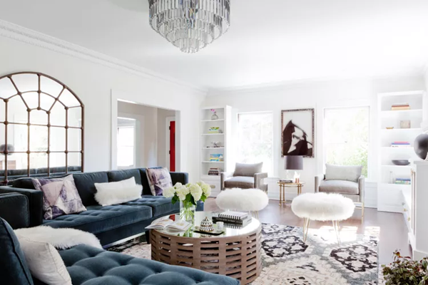layered-contemporary-living-room-with-round-coffee-table-sheepskin-ottoman-wall-art-and-other-accessories